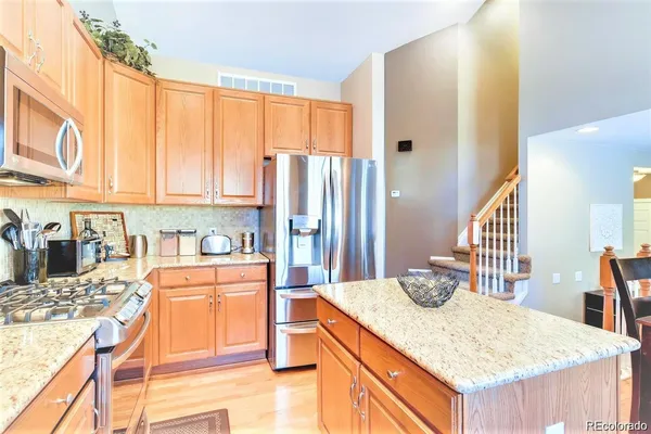 a kitchen with stainless steel appliances granite countertop a refrigerator a stove and a wooden cabinets