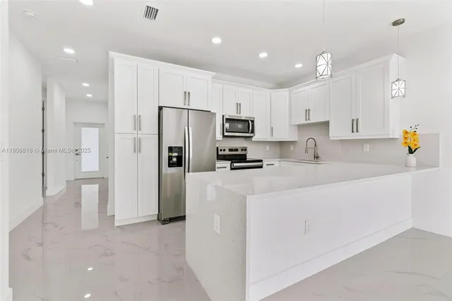 a kitchen with stainless steel appliances refrigerator a microwave and white cabinets