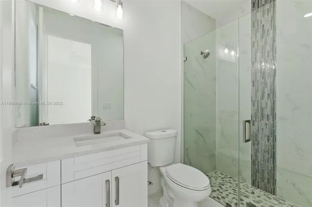 a bathroom with a granite countertop sink a toilet and shower