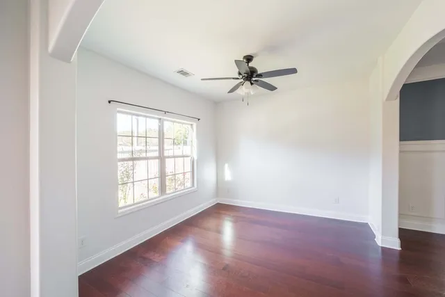 an empty room with wooden floor fan and windows