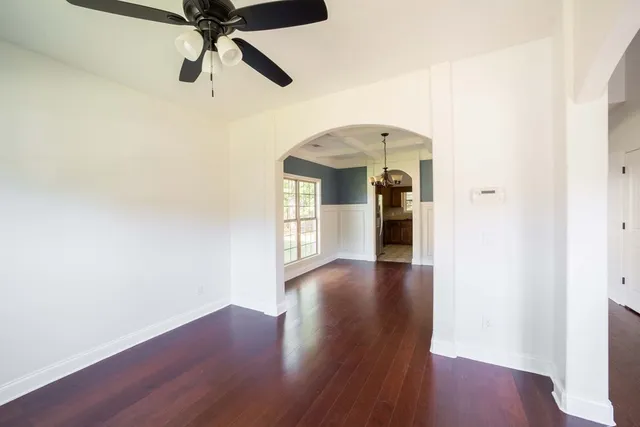 a view of a big room with wooden floor a ceiling fan and windows