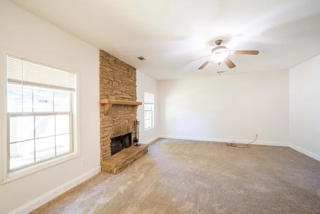 a view of an empty room with a fireplace and a window