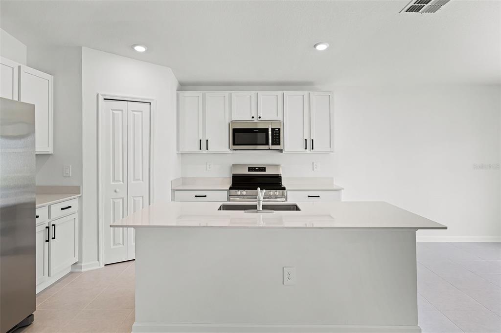 1993 Sarah Street Lake Wales, FL 33859 - Photo 5 of 31 a kitchen with white cabinets and black appliances