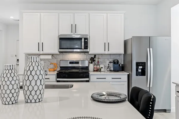 a kitchen with a refrigerator a stove and white cabinets