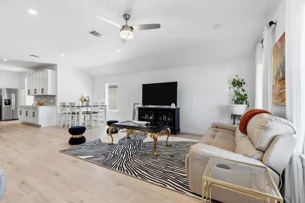 a living room with furniture a flat screen tv and kitchen view
