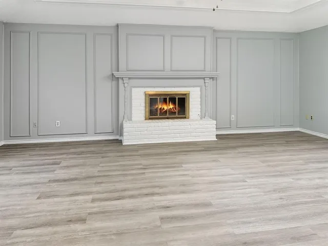a view of an empty room with wooden floor and a fireplace