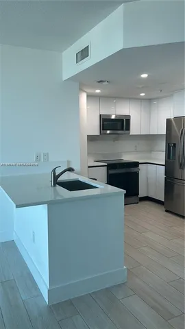 a kitchen with stainless steel appliances granite countertop a sink and a refrigerator