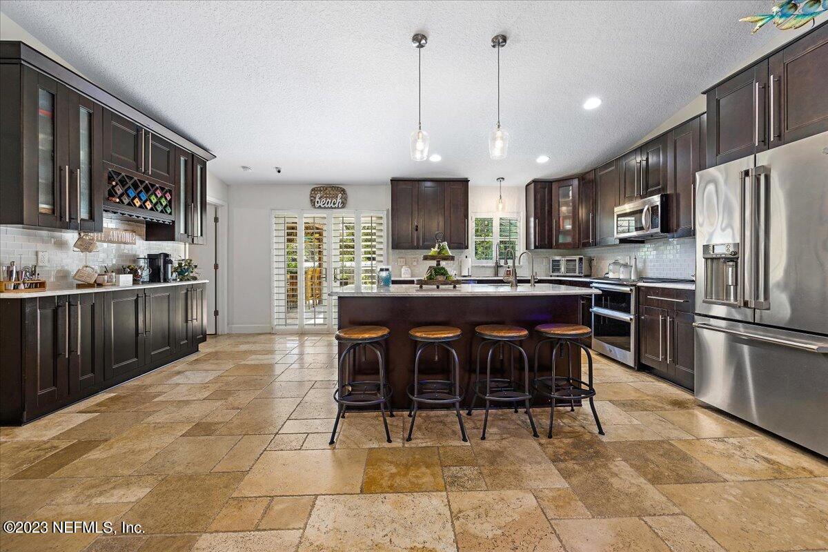 313 Eleventh Street St. Augustine, FL 32084 - Photo 13 of 35 a kitchen with stainless steel appliances granite countertop a stove top oven a sink a dining table and chairs