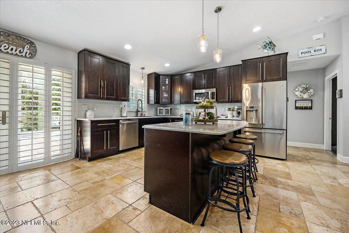 313 Eleventh Street St. Augustine, FL 32084 - Photo 14 of 35 a kitchen with stainless steel appliances granite countertop a refrigerator a stove a sink a microwave and a dining table with wooden cabinet