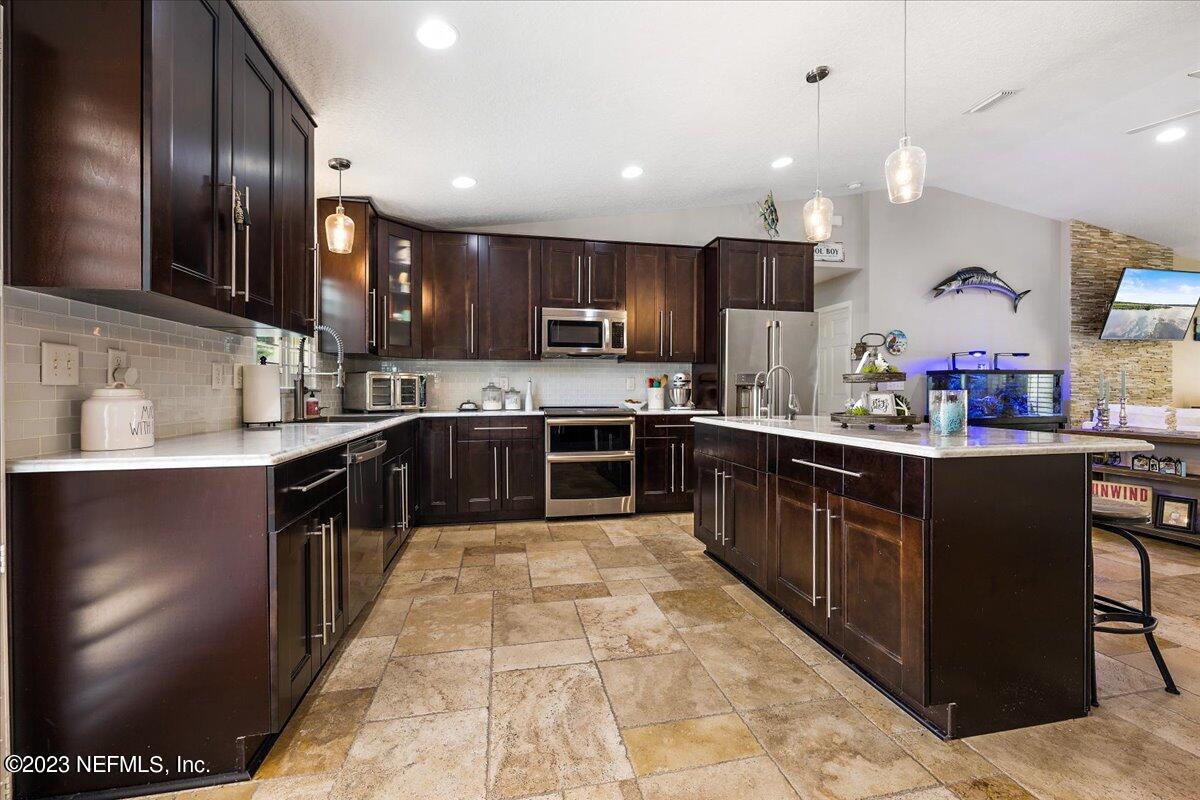 313 Eleventh Street St. Augustine, FL 32084 - Photo 15 of 35 a large kitchen with stainless steel appliances kitchen island granite countertop a stove top oven a sink a counter space and cabinets