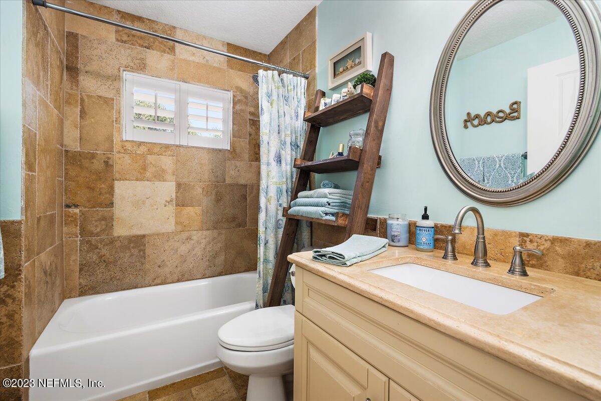 313 Eleventh Street St. Augustine, FL 32084 - Photo 24 of 35 a bathroom with a granite countertop toilet a sink and a mirror