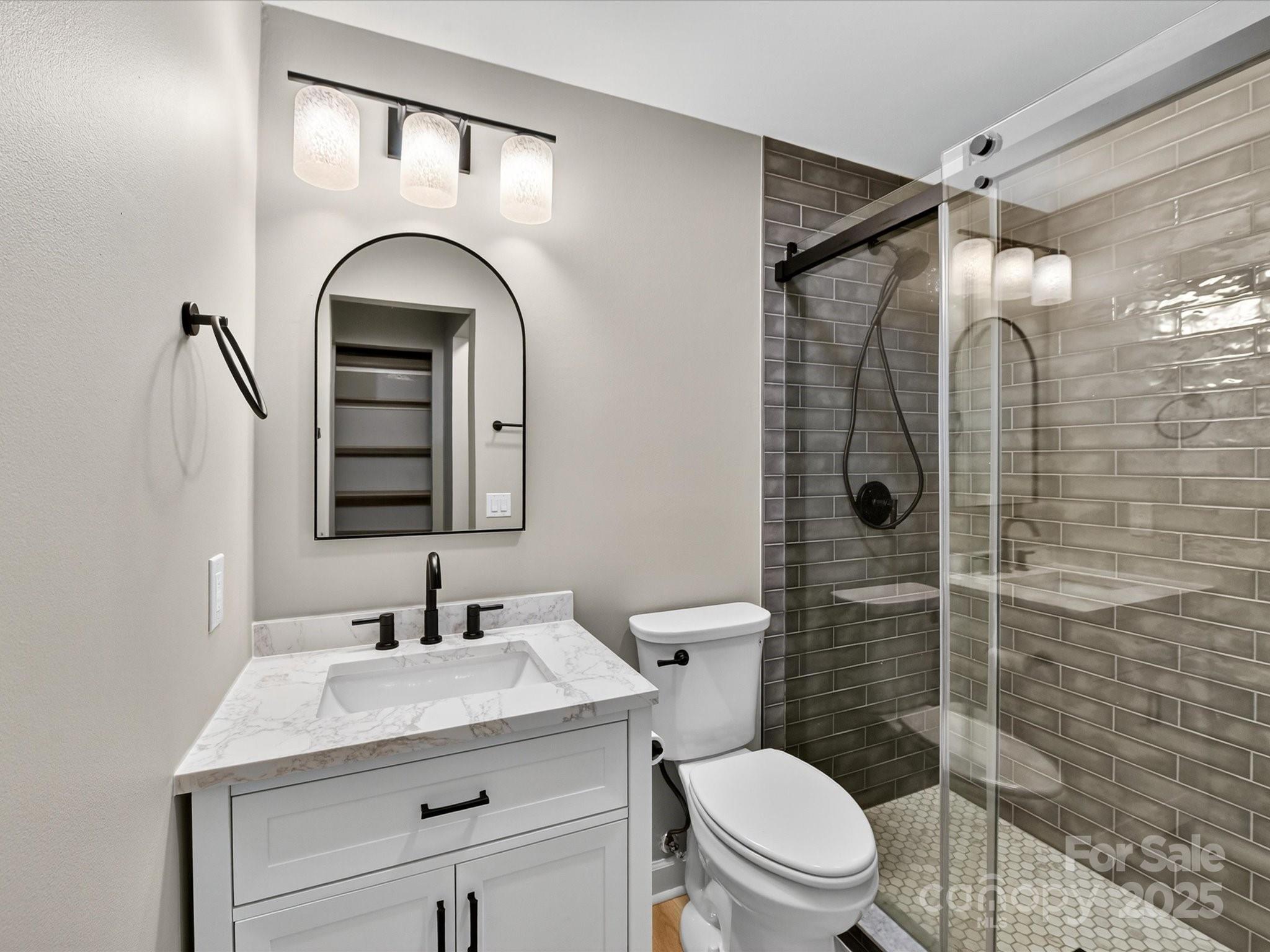 20115 Henderson Road, Unit D Cornelius, NC 28031 - Photo 18 of 44 a bathroom with a granite countertop sink toilet mirror and shower