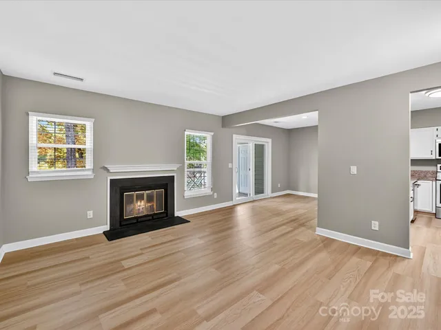 an empty room with wooden floor fireplace and windows