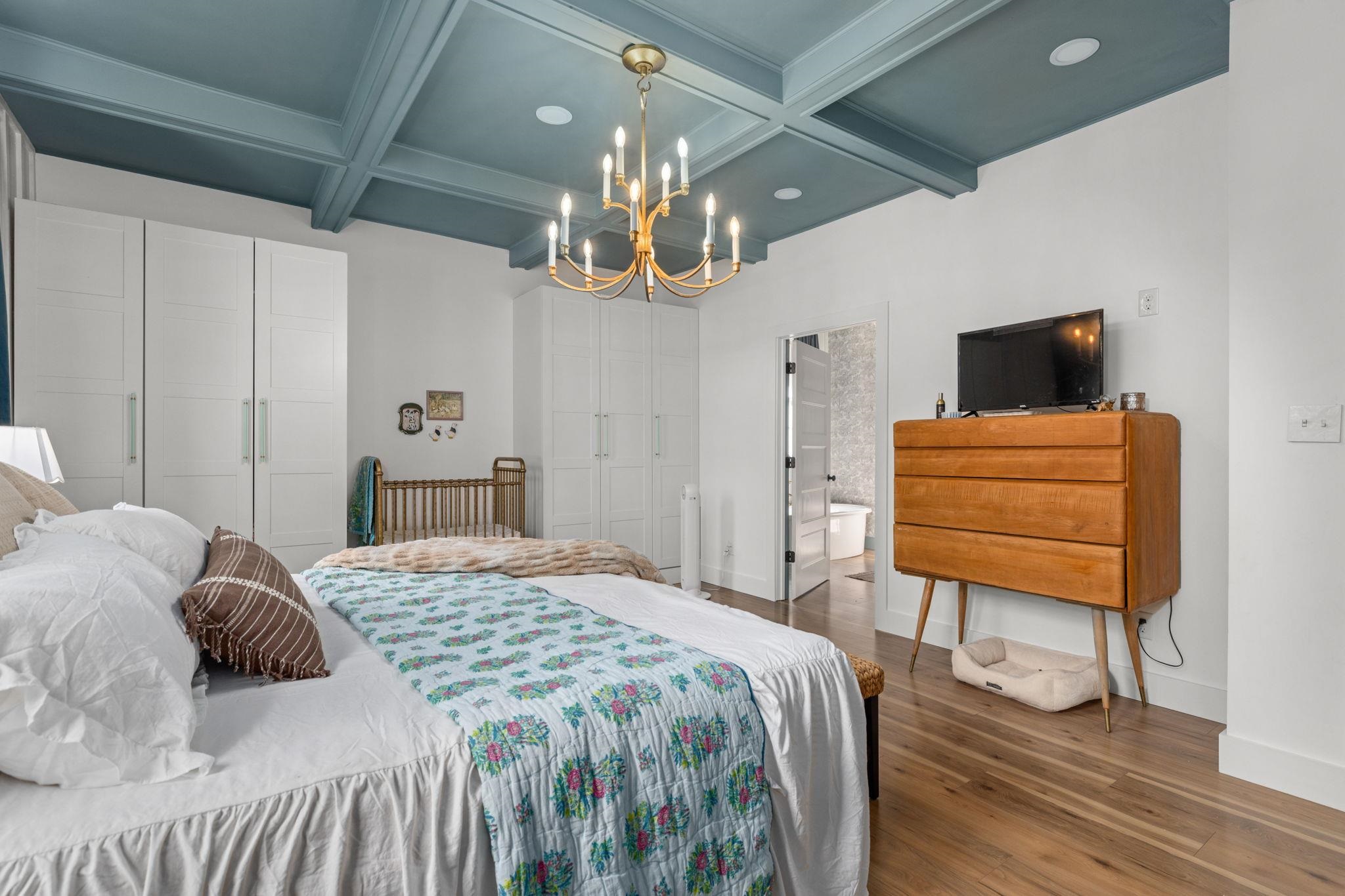 41 County Road 409 Rienzi, MS 38865 - Photo 14 of 40 Bedroom with wood finished floors, beamed ceiling, coffered ceiling, ensuite bath, and a chandelier