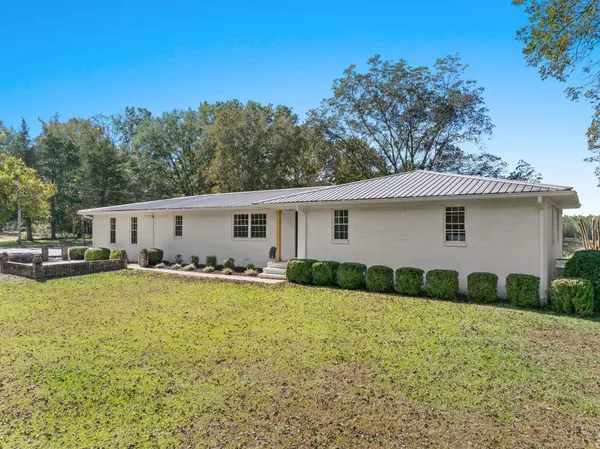 a view of a house with backyard and trees