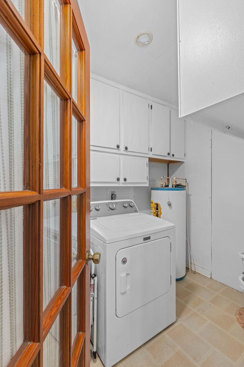 41 County Road 409 Rienzi, MS 38865 - Photo 29 of 40 Washroom with washer / dryer, light tile patterned floors, water heater, and cabinet space