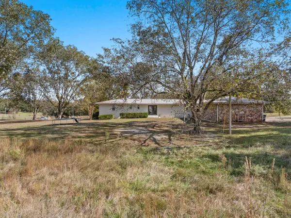 a view of a white house next to a road and trees
