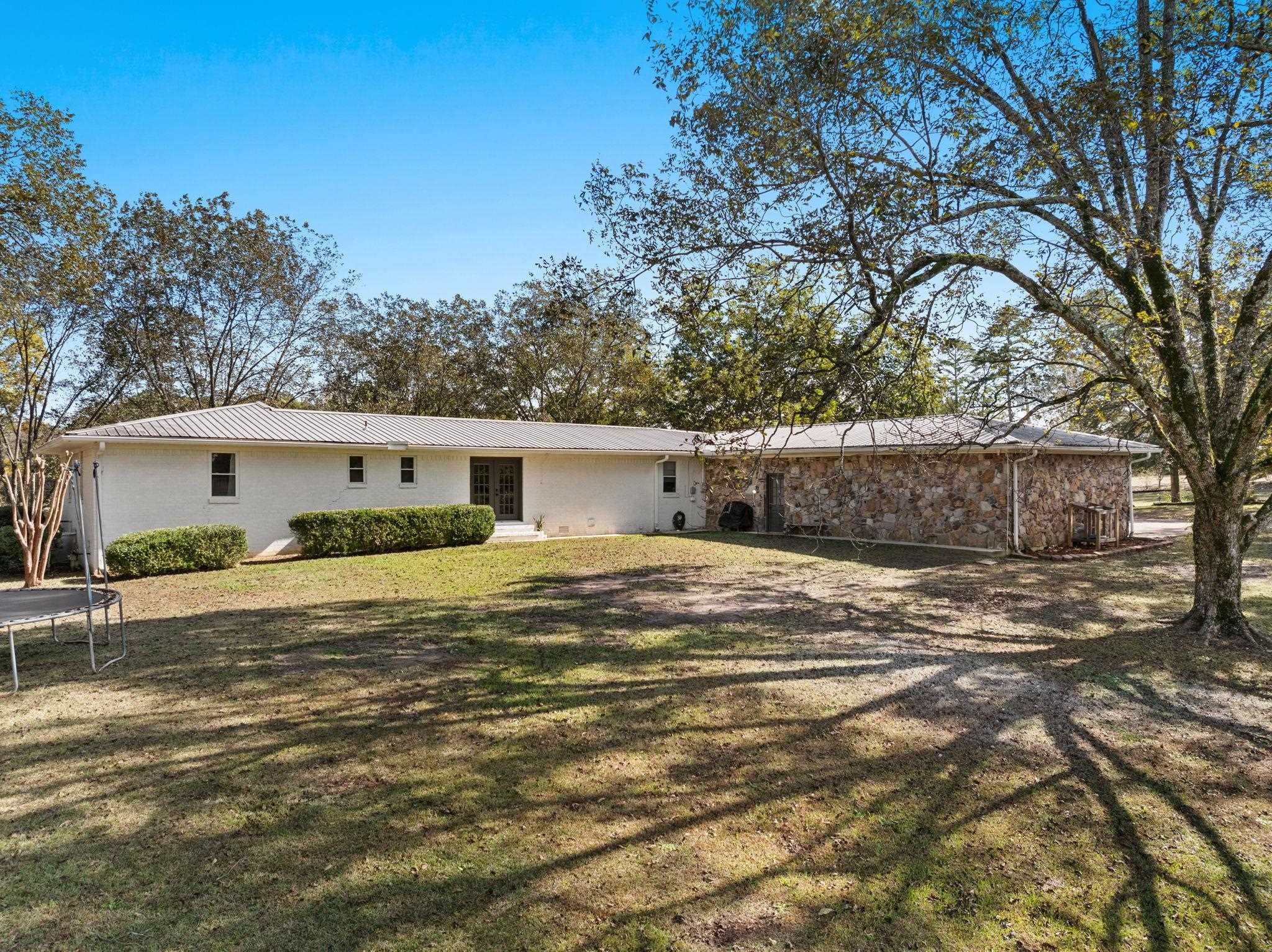 41 County Road 409 Rienzi, MS 38865 - Photo 33 of 40 Back of house featuring a trampoline, a metal roof, and a lawn