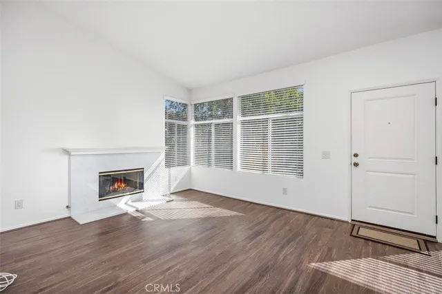 an empty room with wooden floor fireplace and windows