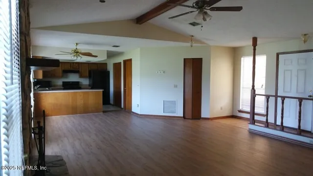 a view of empty room with wooden floor and fan