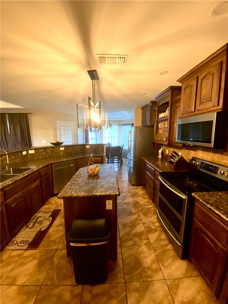1250 Lawrence Trail Alice, TX 78332 - Photo 12 of 40 a kitchen with stainless steel appliances granite countertop a stove a sink and a microwave
