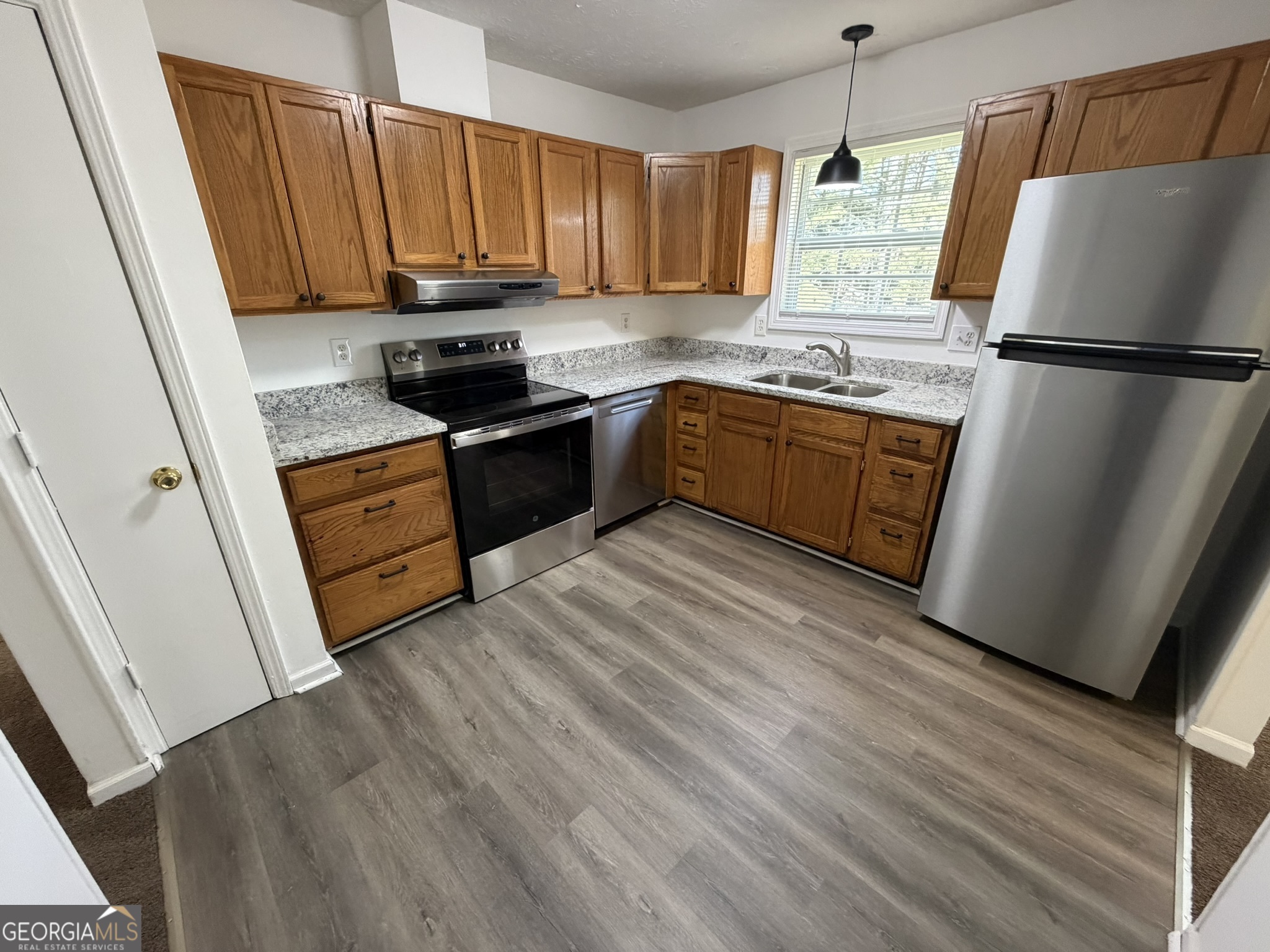 9292 Settlers Grove Road Northeast Covington, GA 30014 - Photo 25 of 110 a kitchen with granite countertop wooden floors white cabinets and stainless steel appliances