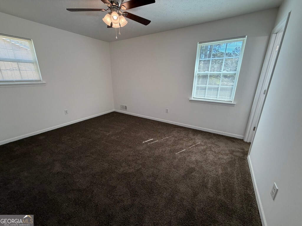 9292 Settlers Grove Road Northeast Covington, GA 30014 - Photo 76 of 110 an empty room with a chandelier fan and windows