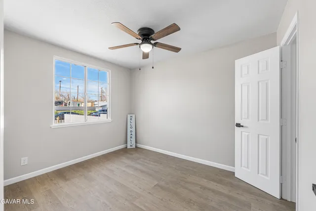 a view of a room with wooden floor and a ceiling fan