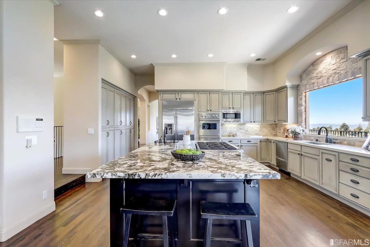 a kitchen with granite countertop kitchen island stainless steel appliances a sink cabinets and wooden floor
