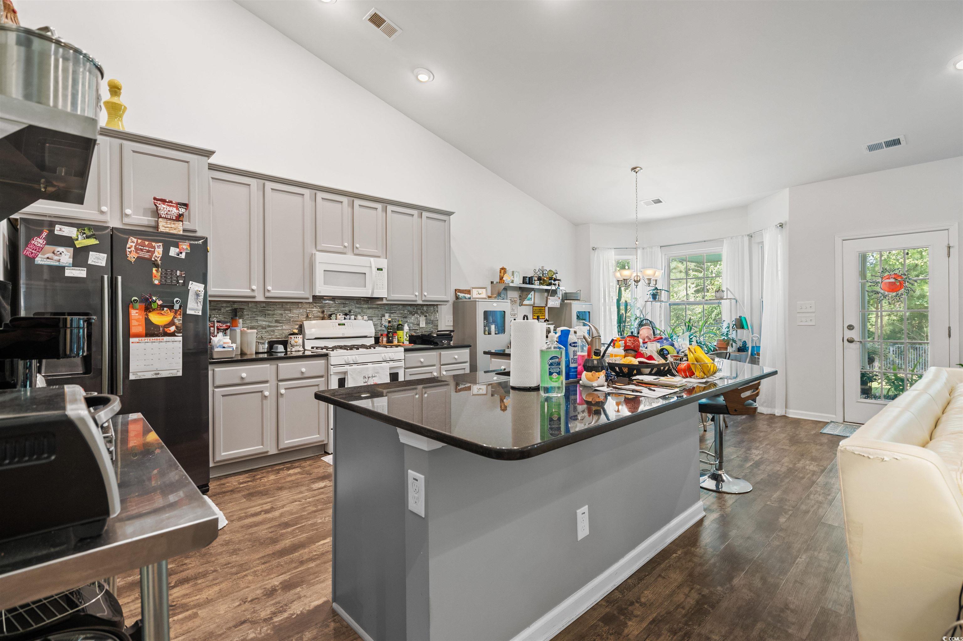 826 Cypress Way Little River, SC 29566 - Photo 16 of 40 Kitchen with gray cabinets, white appliances, an island with sink, dark wood-style floors, and high vaulted ceiling