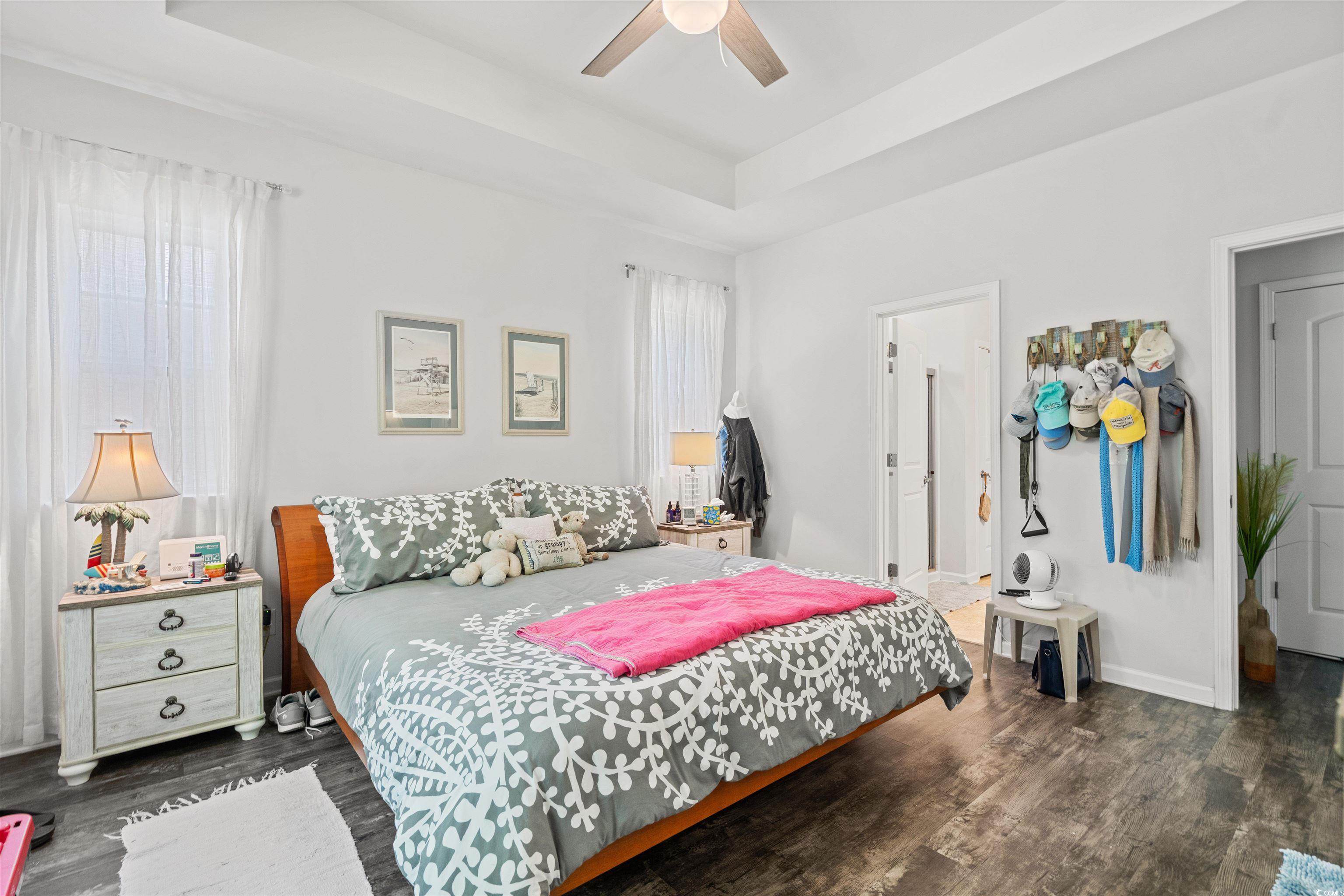826 Cypress Way Little River, SC 29566 - Photo 21 of 40 Bedroom featuring a tray ceiling, dark wood-type flooring, a ceiling fan, and multiple windows