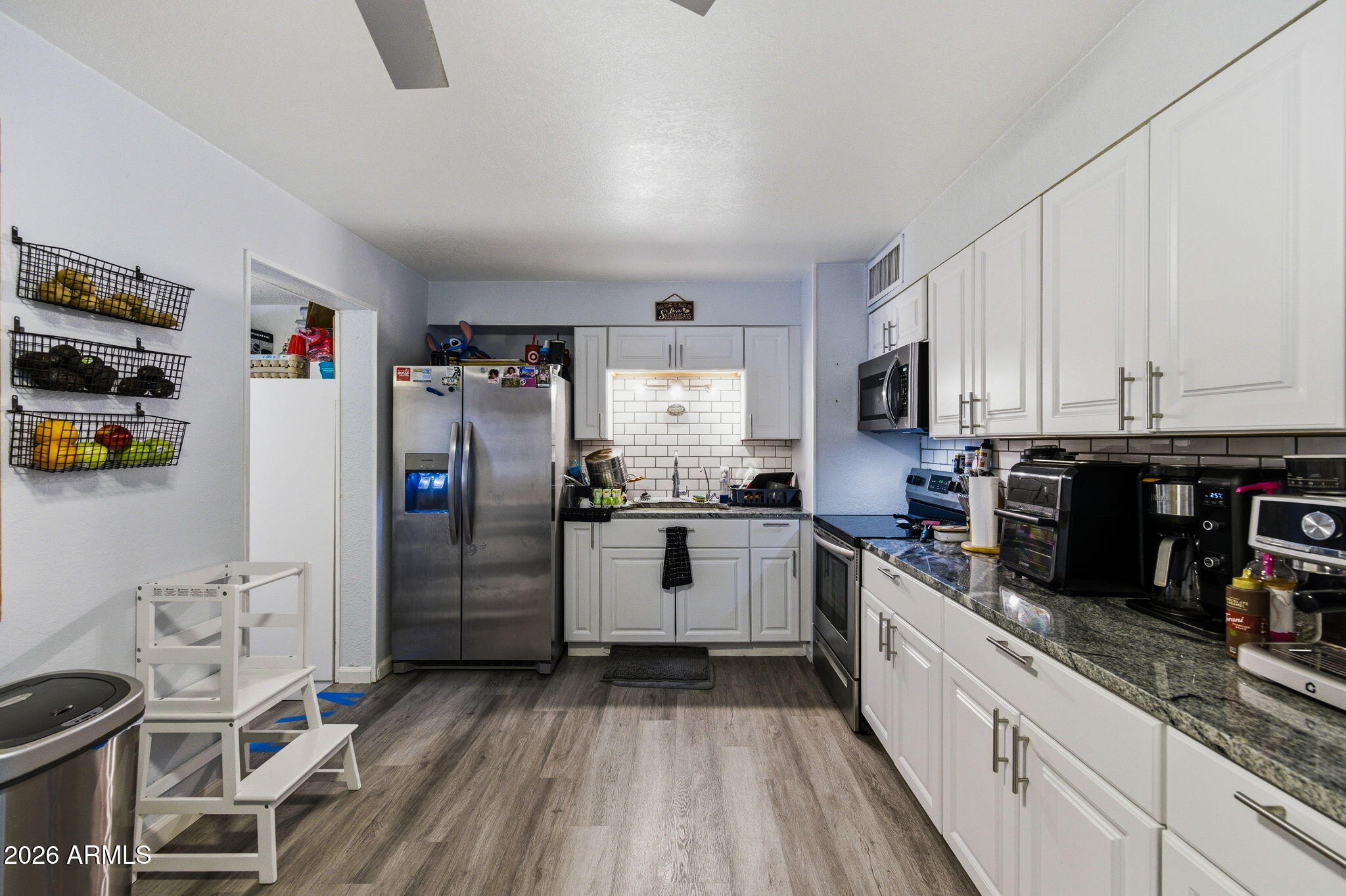 1268 East Rodeo Road Casa Grande, AZ 85122 - Photo 9 of 27 a kitchen with stainless steel appliances granite countertop a refrigerator a stove and white cabinets with wooden floor