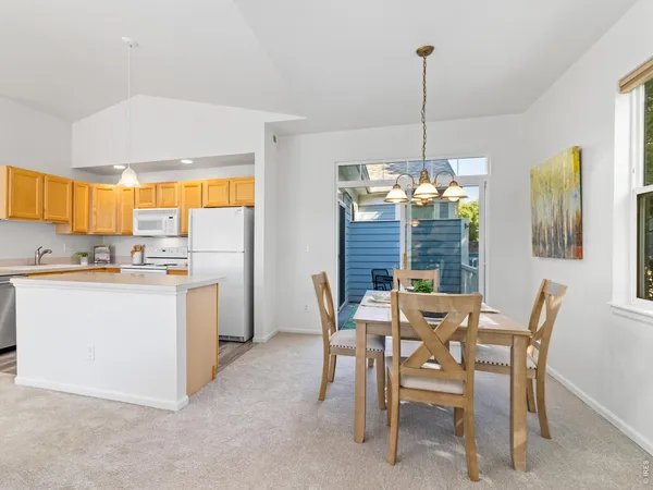 a dining room filled a chandelier and kitchen view