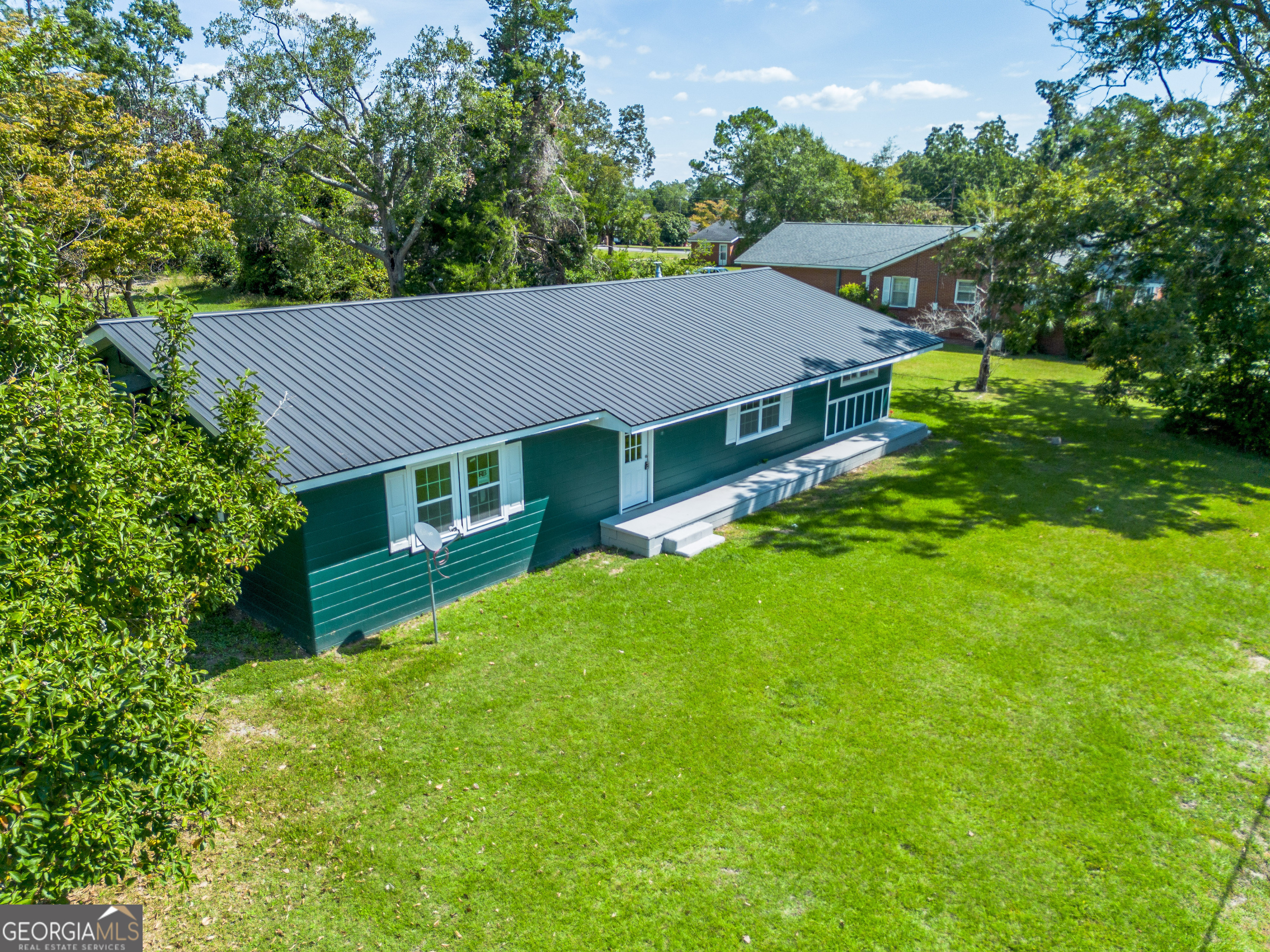 a aerial view of a house next to a big yard and large trees