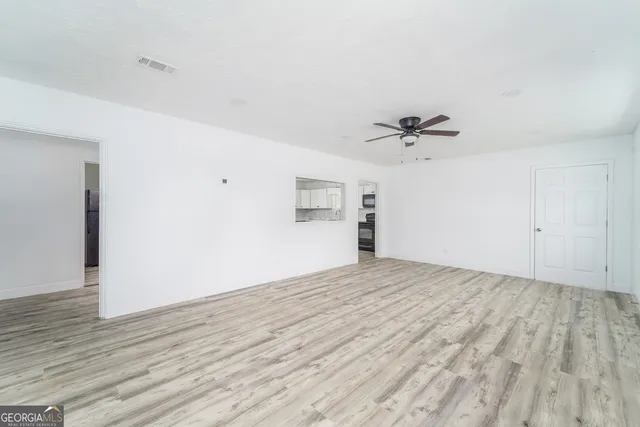 a view of a room with wooden floor and a ceiling fan
