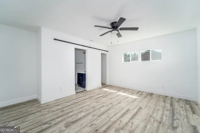 a view of empty room with wooden floor and fan