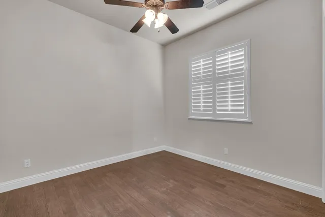 an empty room with a window and a ceiling fan