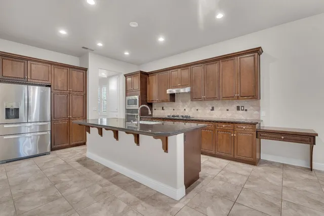 a kitchen with stainless steel appliances granite countertop a sink refrigerator and cabinets