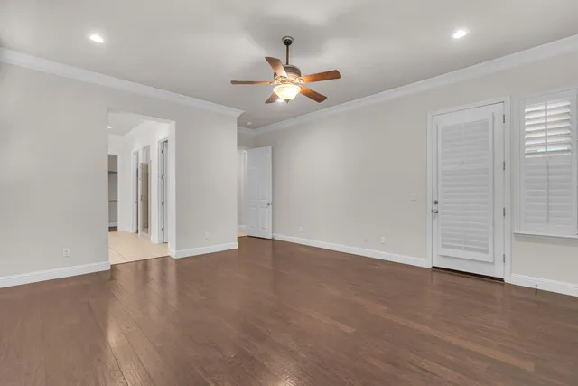 an empty room with wooden floor ceiling fan and windows