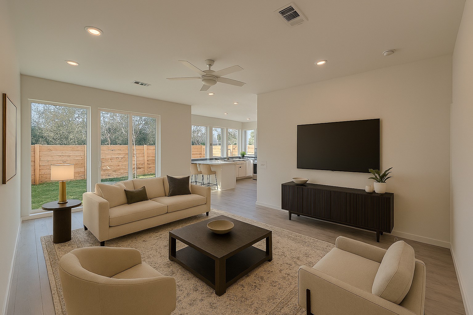 2000 Riverside Farms Road, Unit 8102 Austin, TX 78741 - Photo 1 of 10 This photo showcases a modern, open-concept living area with neutral tones. It features a cozy seating arrangement, a large wall-mounted TV, and ample natural light through expansive windows. The space seamlessly connects to a bright kitchen area, creating an inviting atmosphere for family gatherings or entertaining.