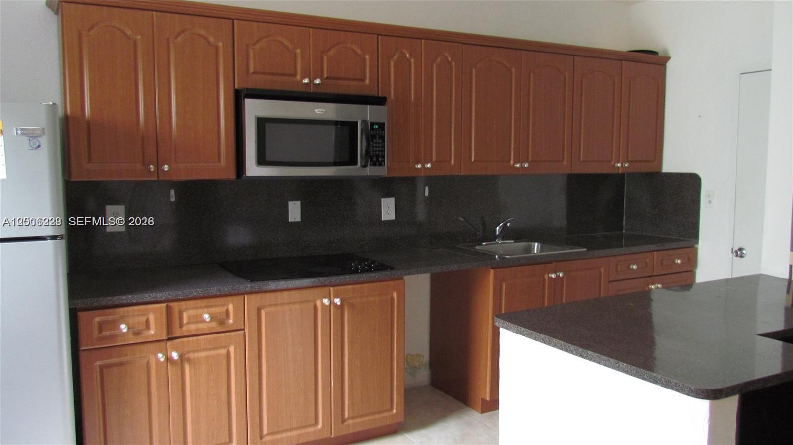 7920 Harding Avenue, Unit 10 Miami Beach, FL 33141 - Photo 4 of 6 a kitchen with stainless steel appliances granite countertop a stove a microwave and a refrigerator