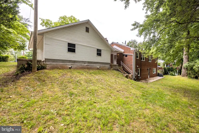 a backyard of a house with a large tree and wooden fence