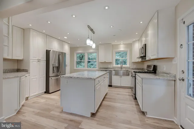 a kitchen with stainless steel appliances granite countertop a refrigerator a stove and a sink