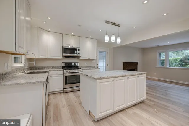 a kitchen with kitchen island granite countertop a stove top oven a sink dishwasher a dining table and chairs with wooden floor