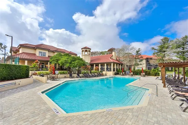 a view of swimming pool with a lounge chairs in front of yellow house