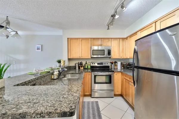a kitchen with stainless steel appliances granite countertop a refrigerator sink stove microwave and cabinets