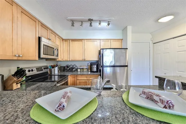 a kitchen with stainless steel appliances granite countertop a refrigerator sink stove and cabinets