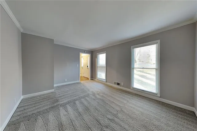 a view of an empty room with wooden floor and window