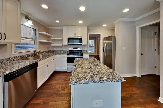 a large kitchen with stainless steel appliances kitchen island granite countertop a large counter top and wooden floor