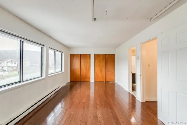 a view of an empty room with wooden floor and a window